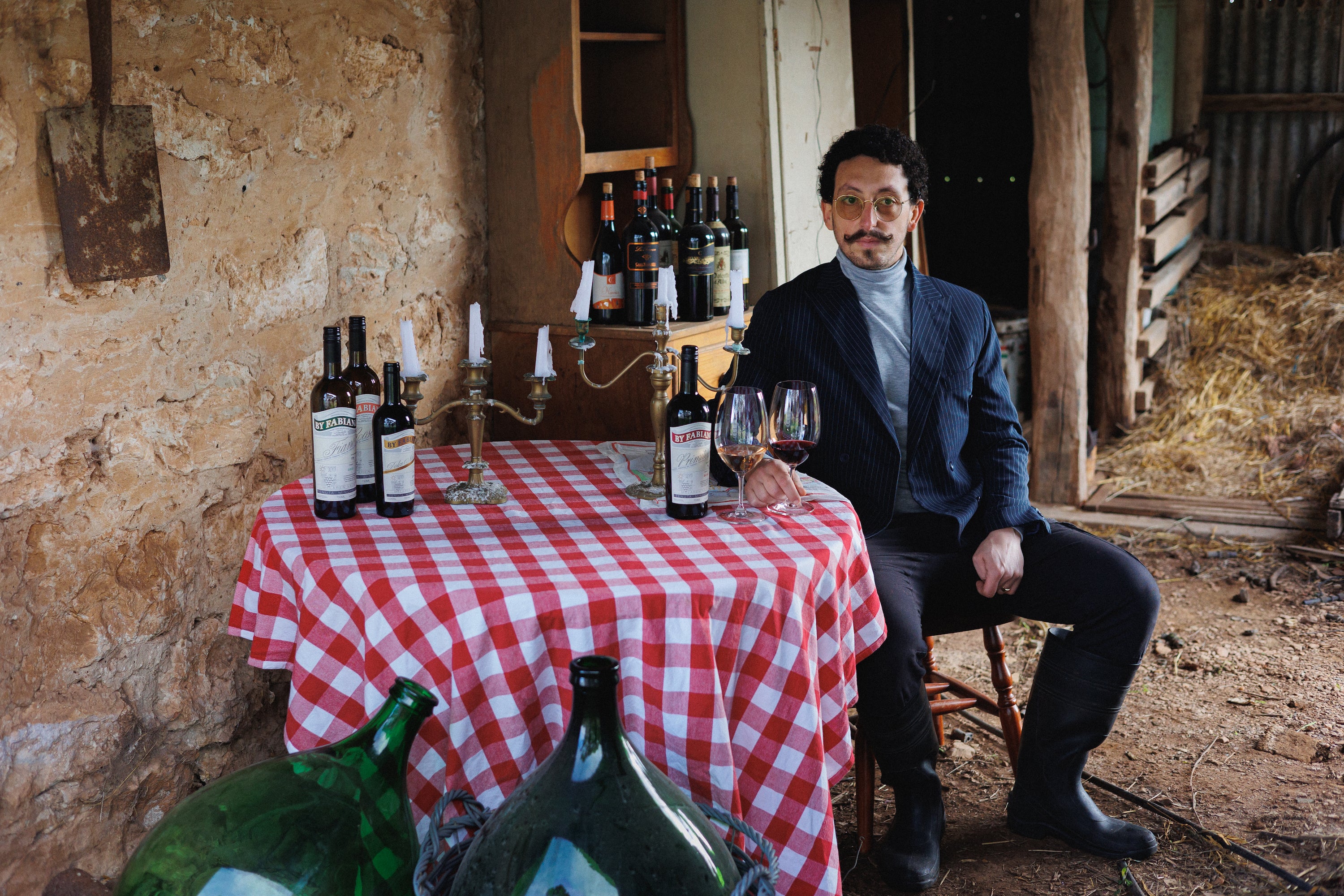 Fabiano sitting at a table with several bottles of By Fabiano wines and several glasses filed with wine.